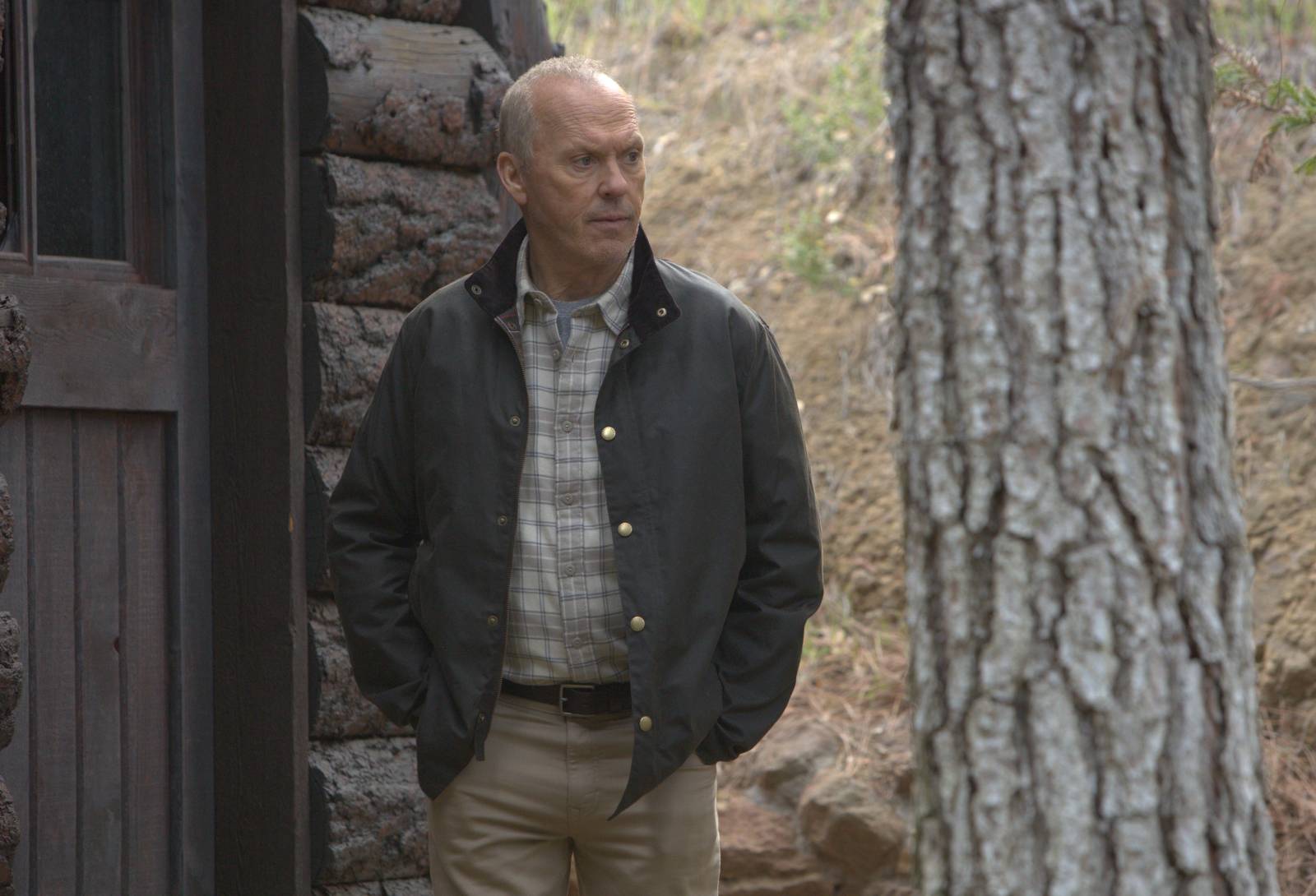 Michael Keaton na frente de uma cabana na floresta